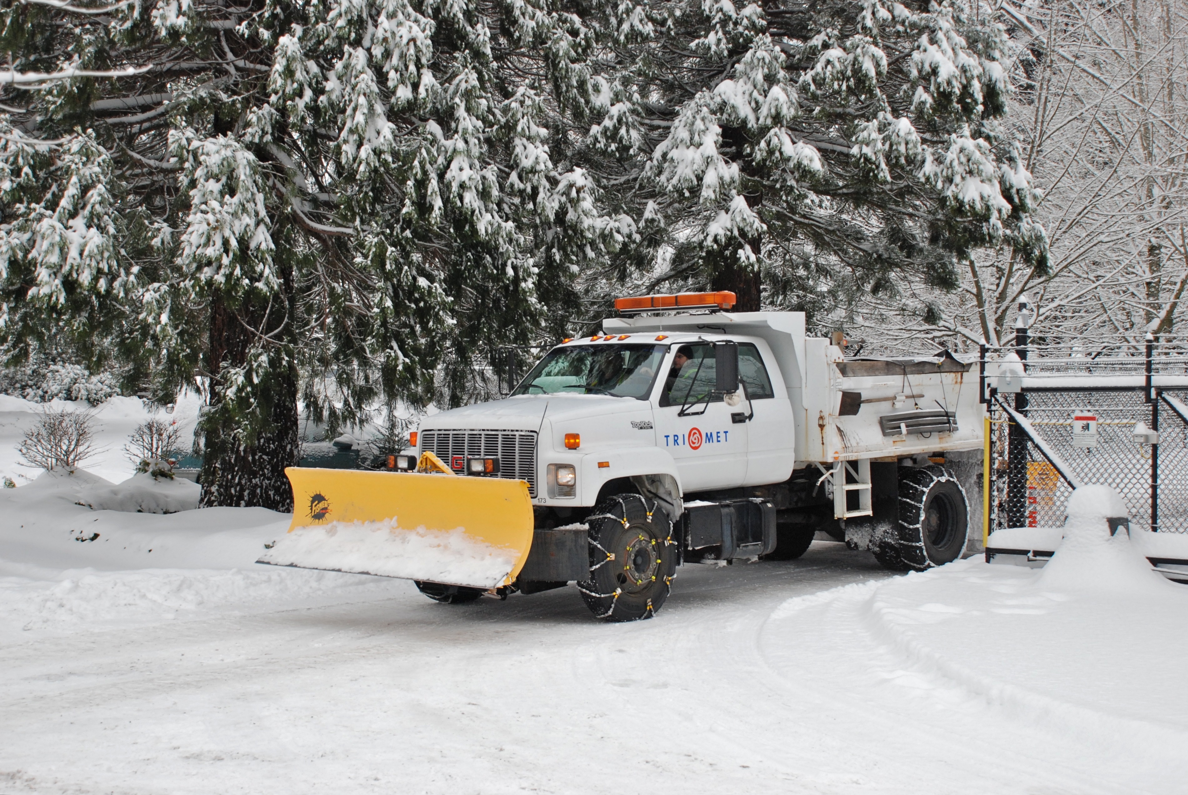 Small dump truck equipped with a snow plow on the front and with tire chains of two different types. TriMet (Portland, Oregon, transit system), Dec. 2008.